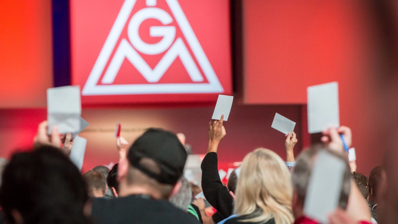 Delegierte auf dem Gewerkschaftstag 2015 der IG Metall bei einer Abstimmung, im Hintergrund das Logo der IG Metall