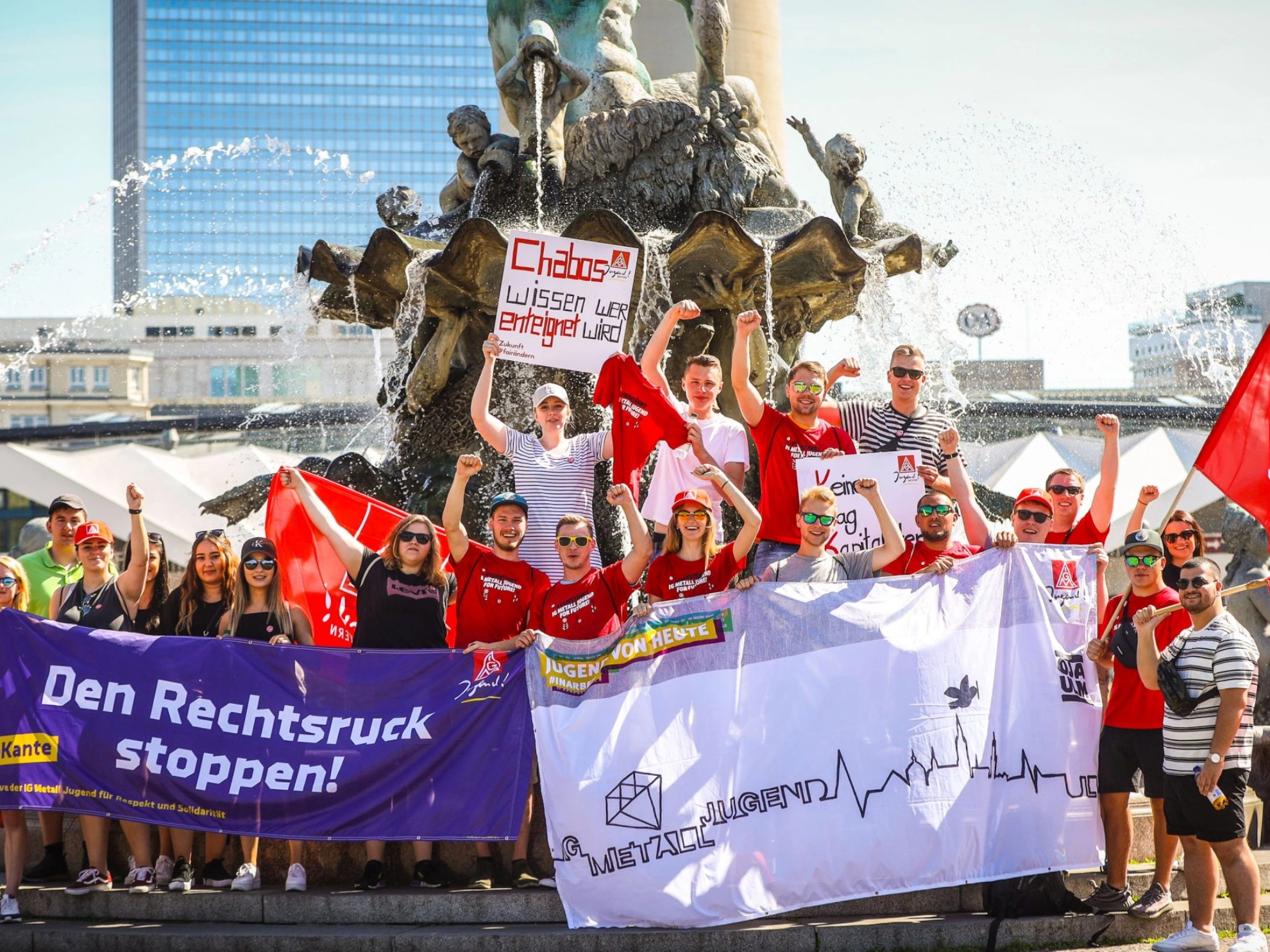 eine Gruppe der IG Metall Jugend posiert mit Bannern auf der FairWandel-Kundgebung vor einem Brunnen in Berlin 